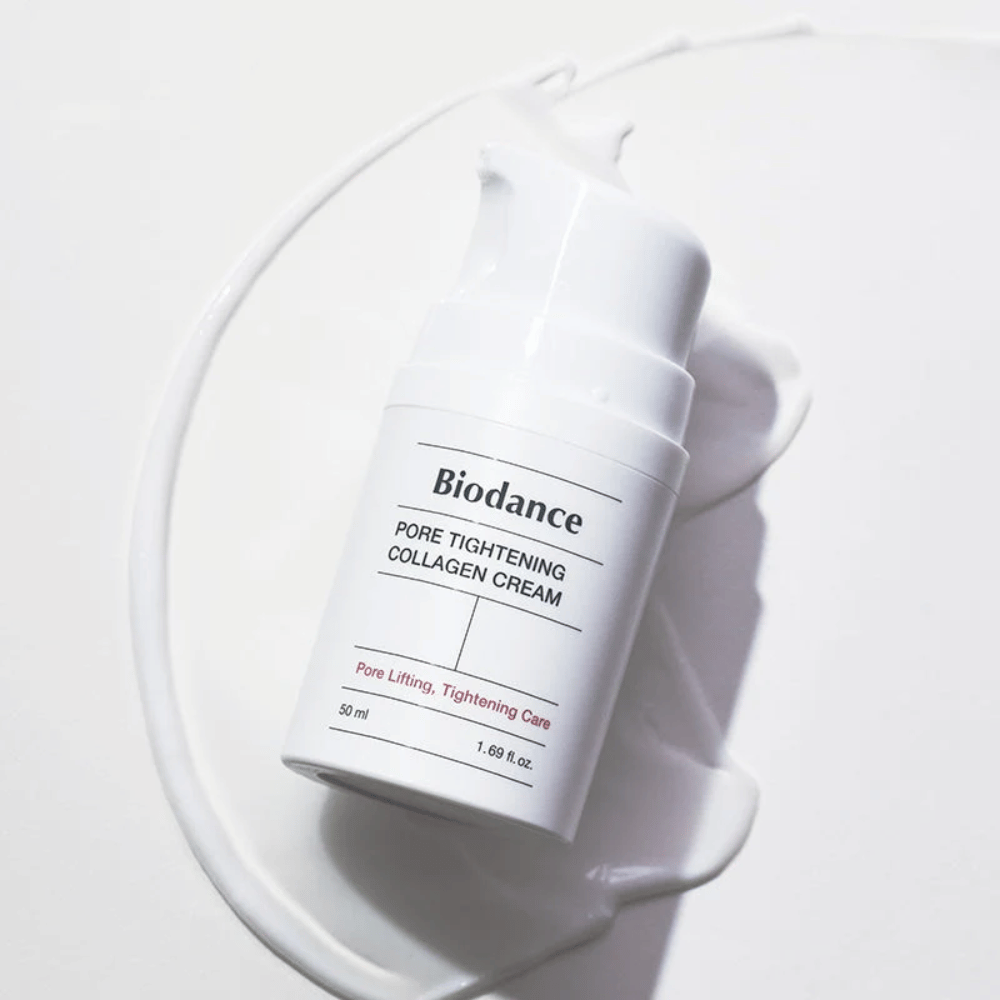 Biodance Pore Tightening Collagen Cream en un frasco de bomba blanco, acostado sobre un remolino de crema blanca.