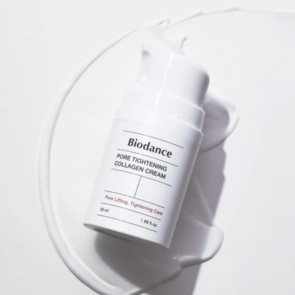 Biodance Pore Tightening Collagen Cream en un frasco de bomba blanco, acostado sobre un remolino de crema blanca.