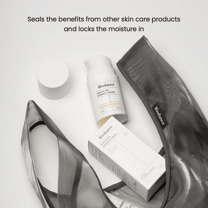 Biodance Skin-Glow Essence Cream en foco junto con el empaque del producto y un neceser negro transparente, con texto arriba que enfatiza la capacidad de la crema para encapsular la humedad y potenciar el efecto de otros productos de cuidado de la piel.